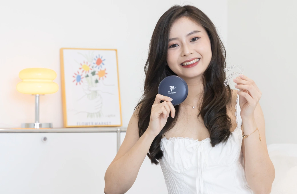 Woman smiling and holding Dr Clear Aligners case and clear aligners.
